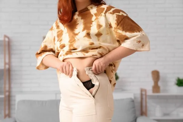 Image of woman trying to do her trousers up after pregnancy weight gain Kingston-upon-Hull