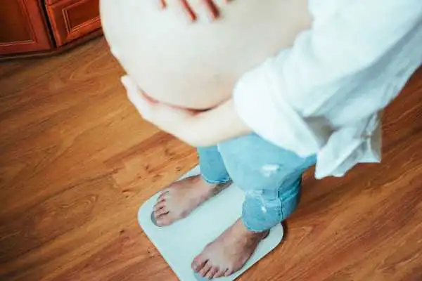 Image of woman weighing herself and experiencing weight gain through pregnancy Kingston-upon-Hull